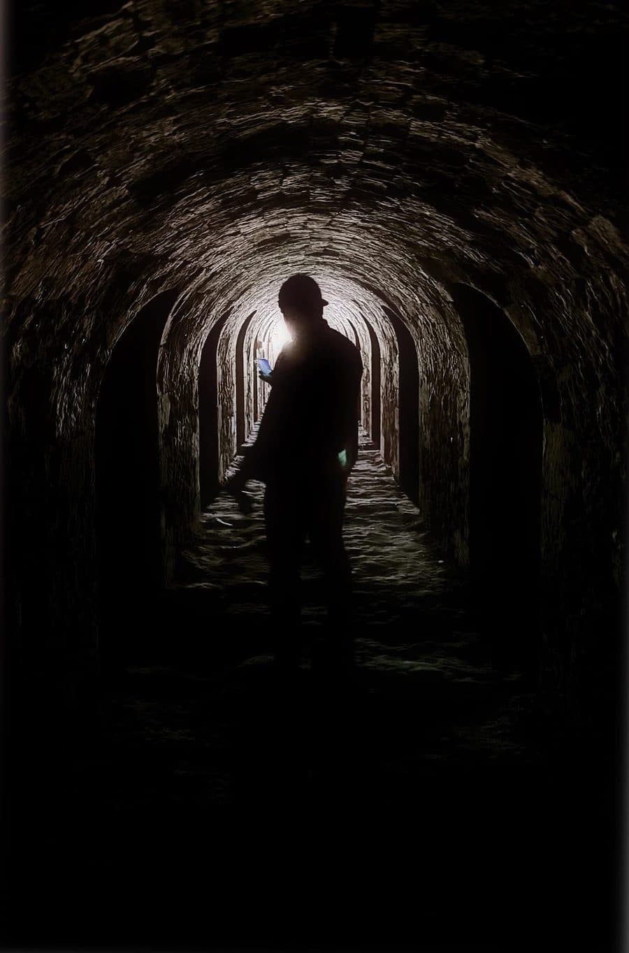 Damien Etancelin en silhouette dans une galerie voûtée